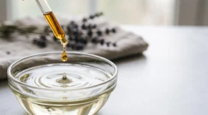 Flacon d'huile essentielle laissant tomber une goutte dans un flacon d'huile végétale, symbole de dilution sécurisée