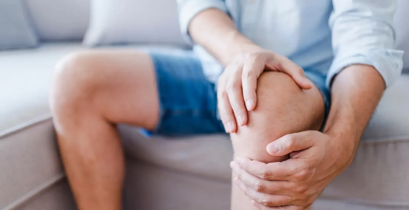 Une personne appuie doucement autour de son genou assise au bord d'une table de soins.
